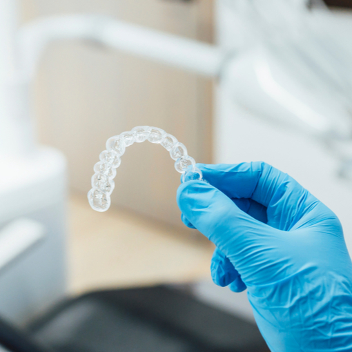 shutterstock_1535696777 woman placing her Invisalign trays on her teeth