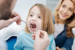 dentist, young girl and mother in a dental check-up