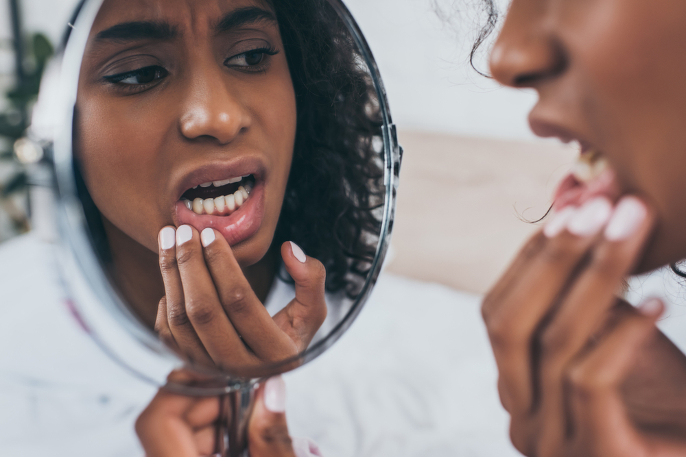 woman looking in the mirror to see if she can see why she's experiencing tooth pain