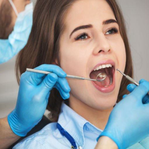Shutterstock_444243844 woman placing her Invisalign trays on her teeth