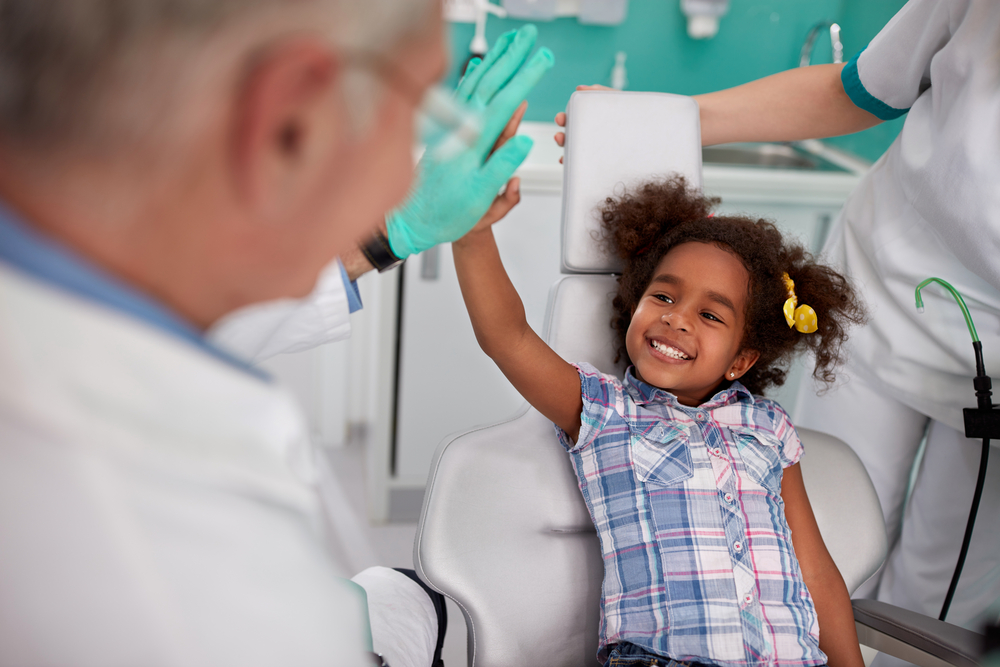 pediatric dentist high fiving a young patient