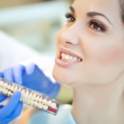 shutterstock_180923525 woman placing her Invisalign trays on her teeth