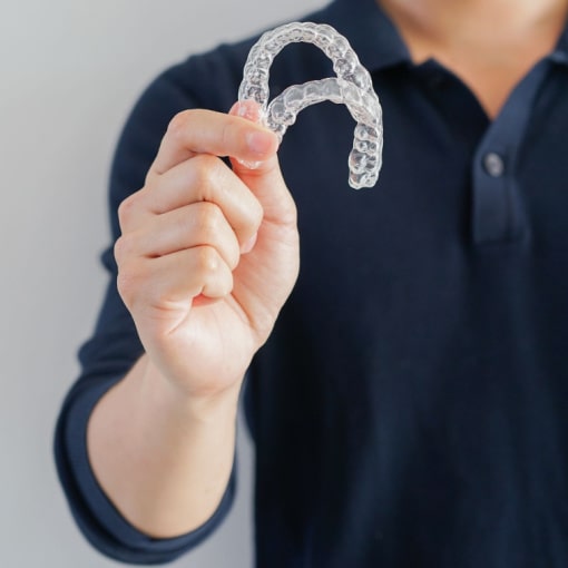 Man Holding Up Two Trays of Invisalign Man Holding Up Two Trays of Invisalign