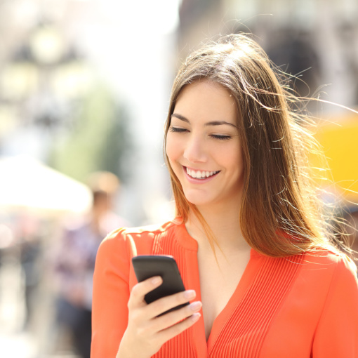 Woman Smiling With Invisalign Woman in orange shirt smiling with Invisalign on her phone