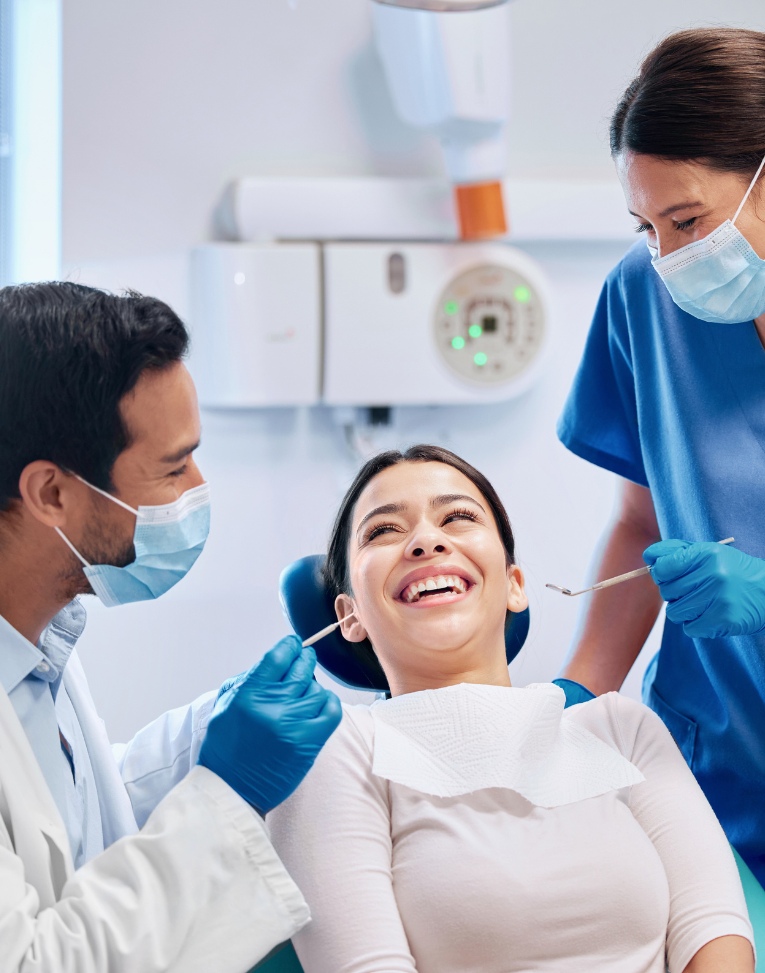 Woman in orange shirt smiling with Invisalign on her phone
