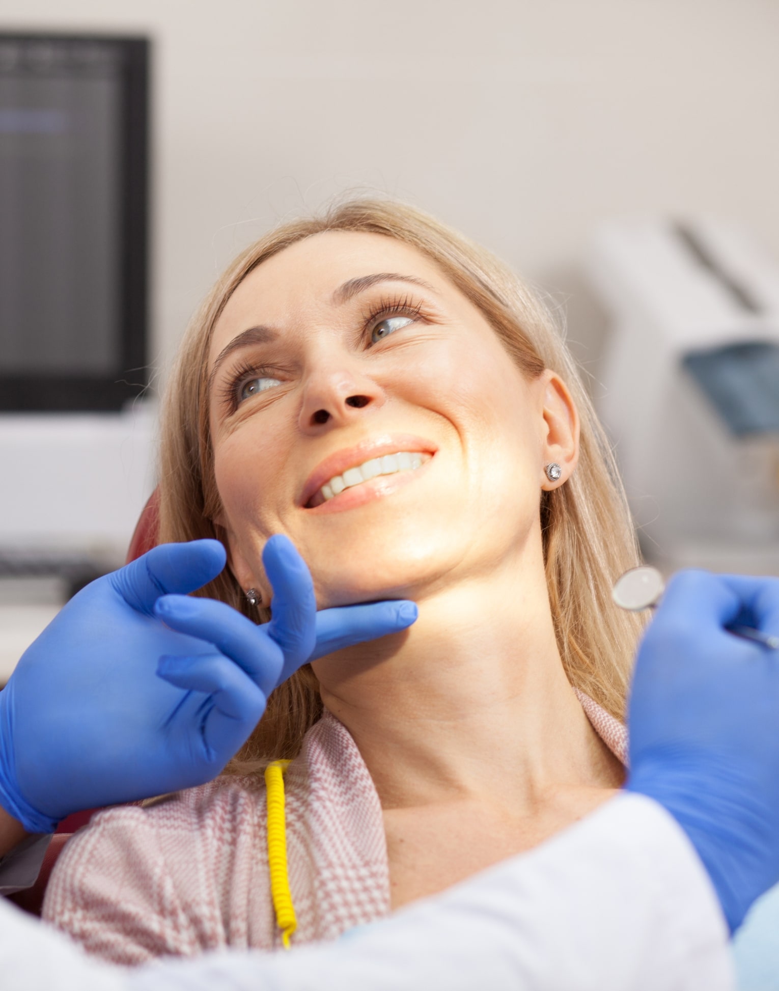 dental service Woman in orange shirt smiling with Invisalign on her phone