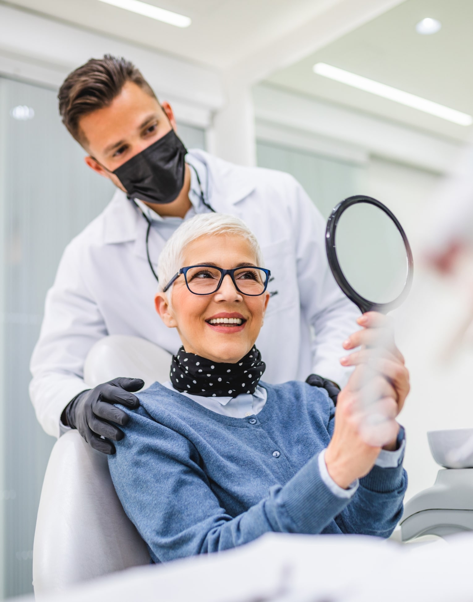 Woman in orange shirt smiling with Invisalign on her phone