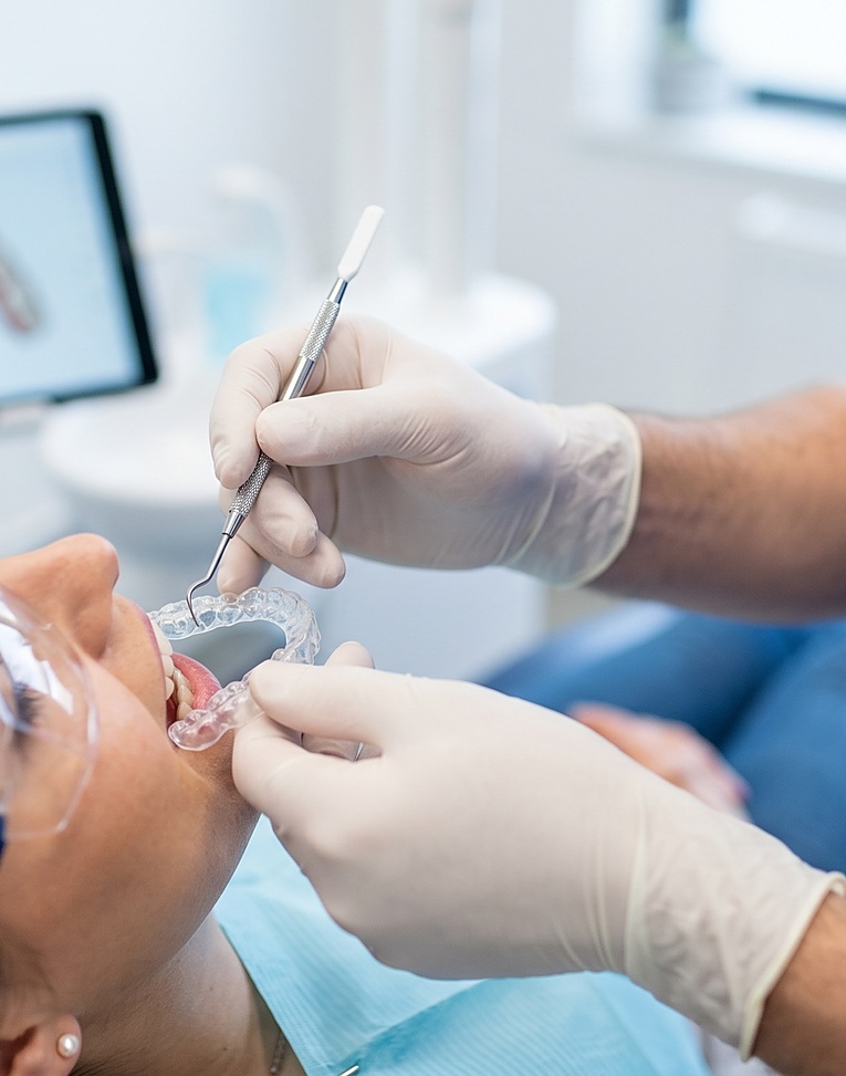 Dentist fitting clear aligner to patients teeth in a modern dental clinic