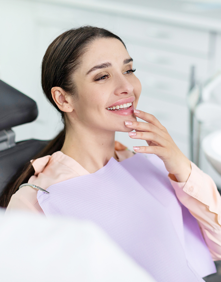 Smiling woman looking in mirror after dental procedure